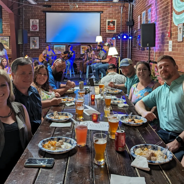 RPS team members and their spouses at a concert event, sitting at a table in front of the stage